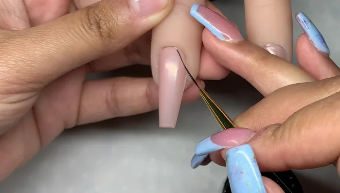 Use the long liner brush to create long straight lines across the nail in one stroke, maintaining good balance and minimal pressure for thin lines.