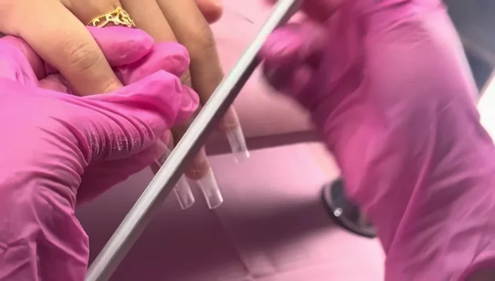 Shape the top of the nail tips using an 80 by 80 Marot nail file to create a subtle moon curve.