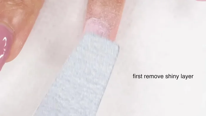 Remove the shiny top coat using a nail file (180 grit), e-file, or buffing block (medium grit).