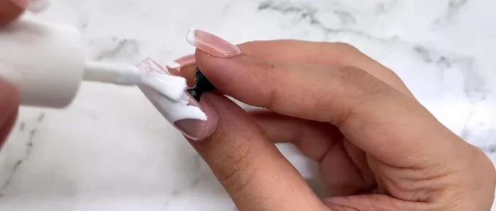 Apply white gel polish, following the dotted line for a clean, precise application.