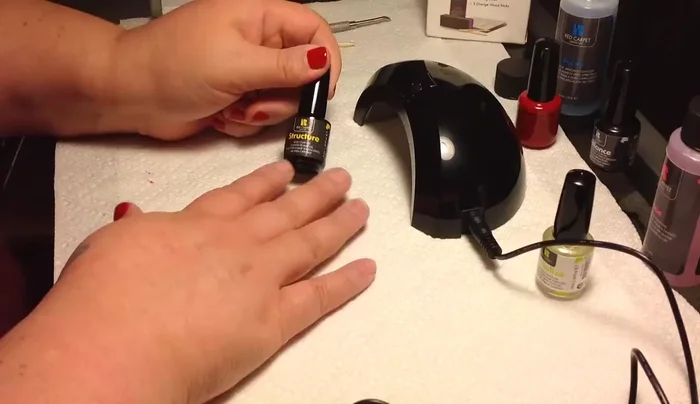 Applying yellow nail base coat with LED lamp