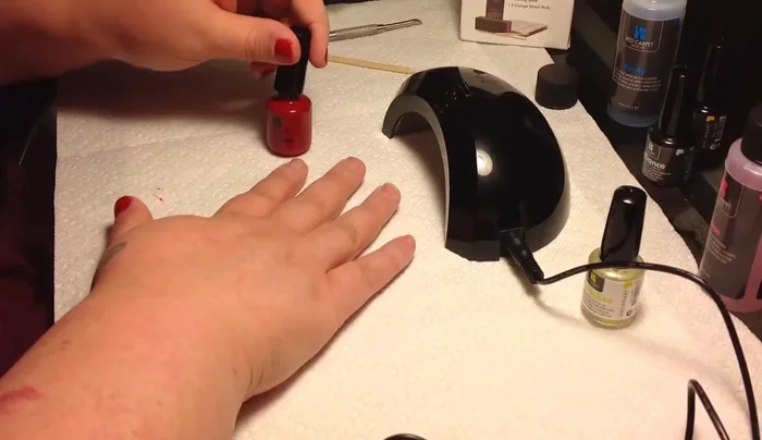 Applying red nail polish with LED lamp