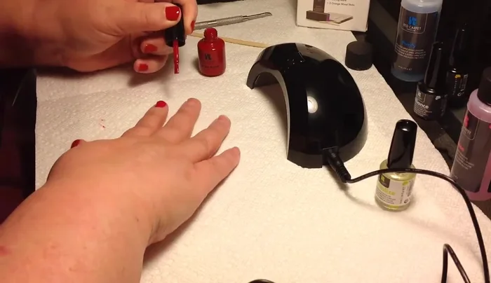 Applying red nail polish with LED lamp