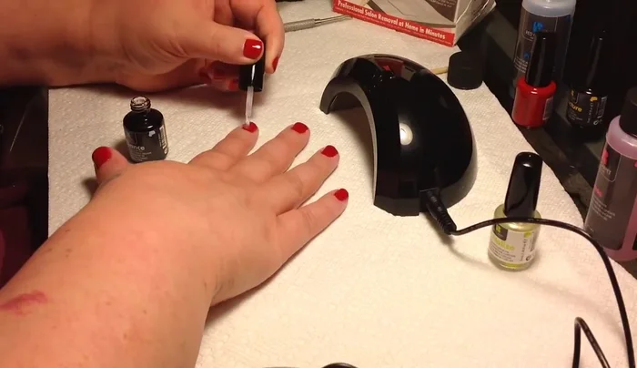 Applying top coat to red nails