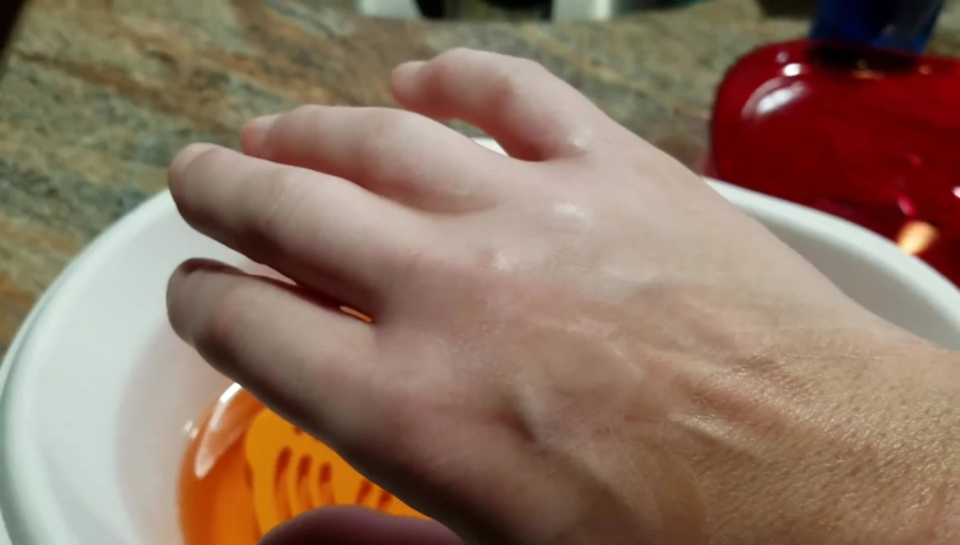 Applying the plastic bag and glove over the wax-coated hand.