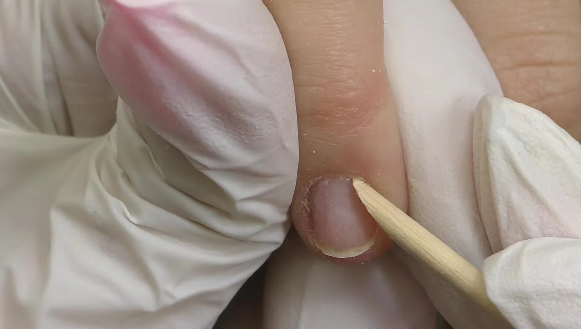 Using an orangewood stick to push back the cuticles.