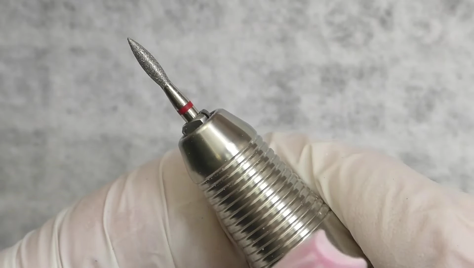 The nail technician using a flame-shaped diamond bit to clean the cuticle area and sidewalls.
