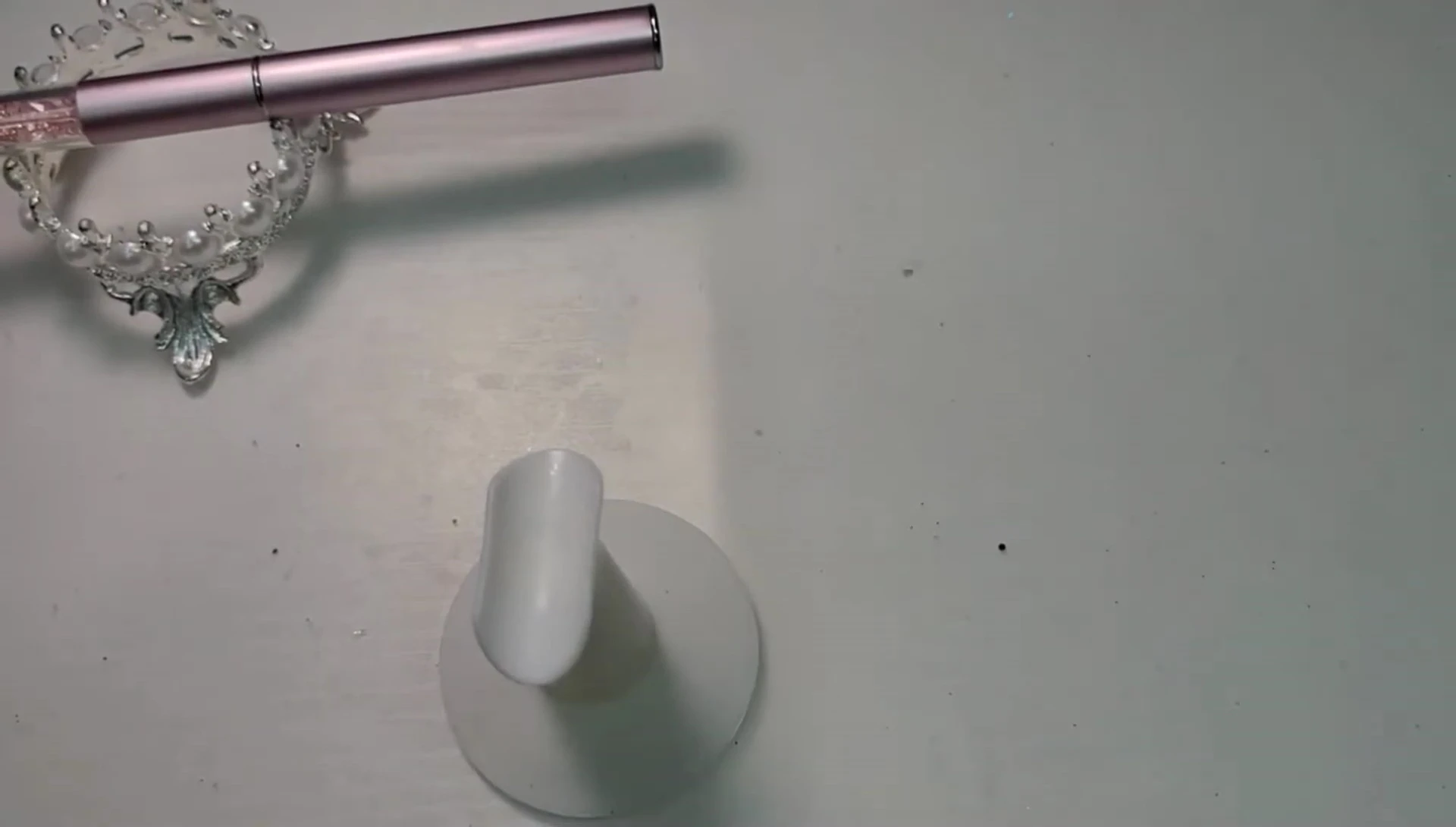 Demonstrating the process of rolling and pinching a nail form to achieve the correct shape.