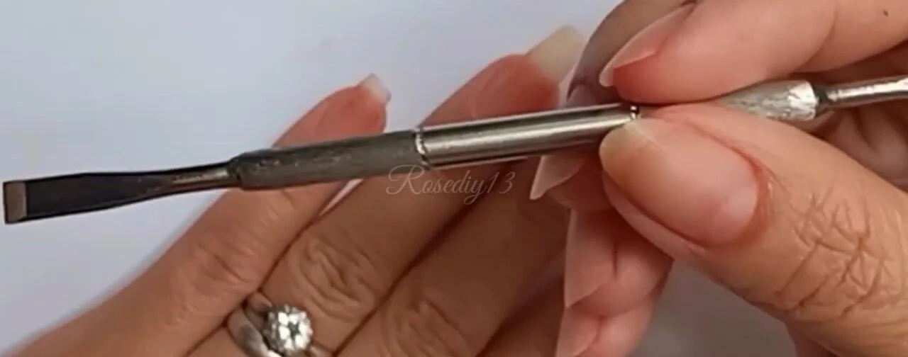 Using the nail pusher to push back cuticles