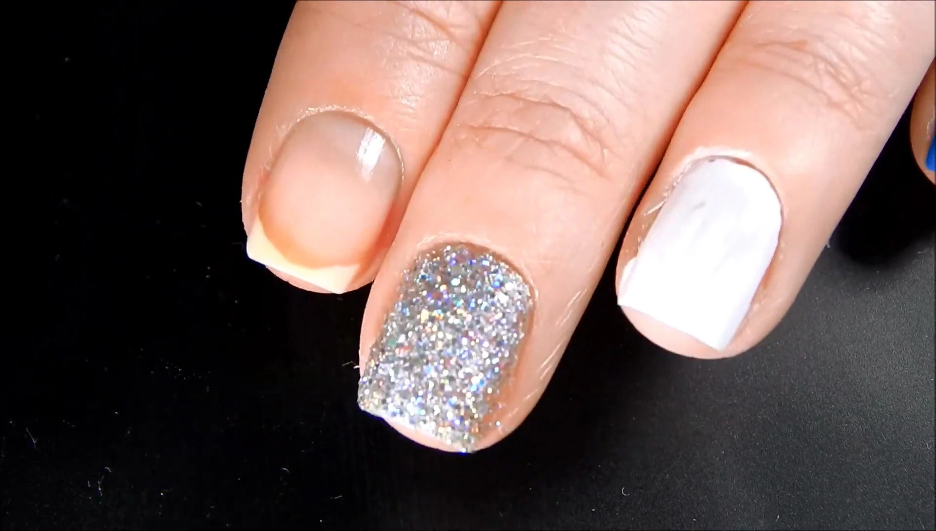 A nail with glitter polish, before the remover is applied.