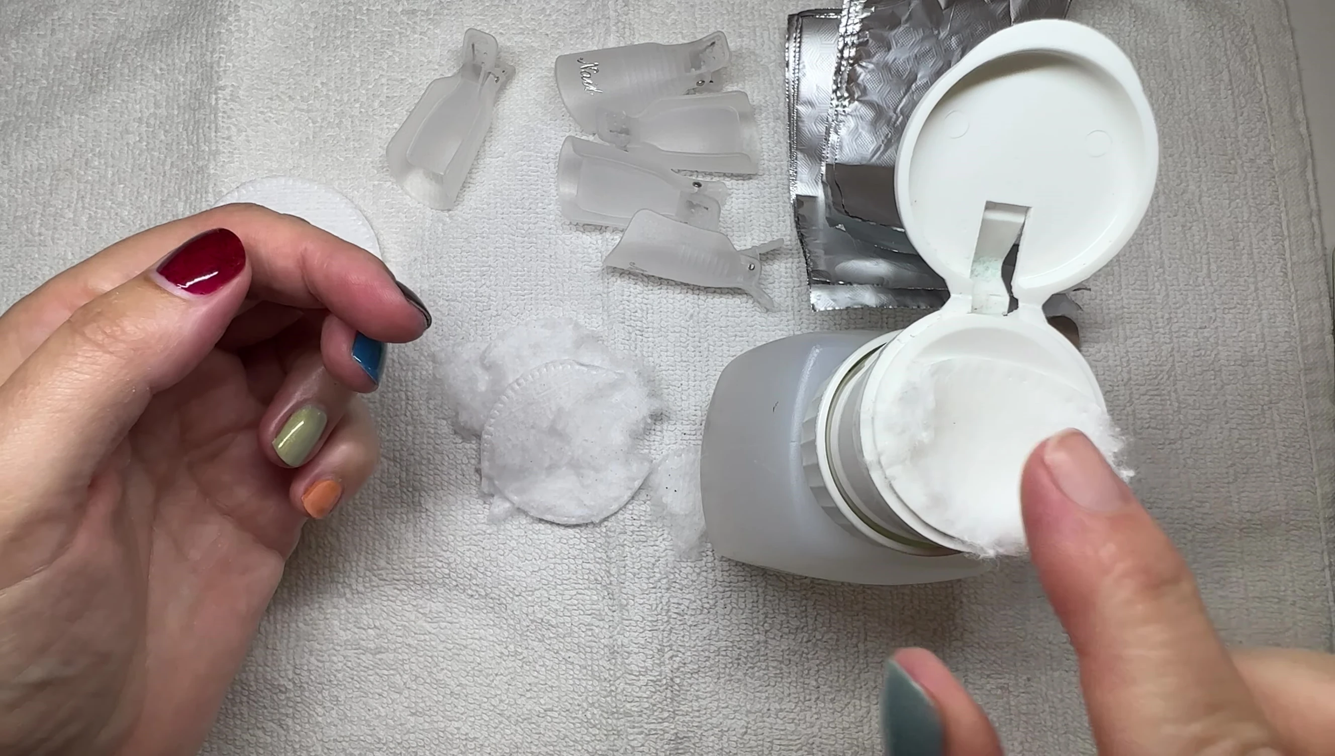 Acetone-soaked cotton pad being applied to a nail.
