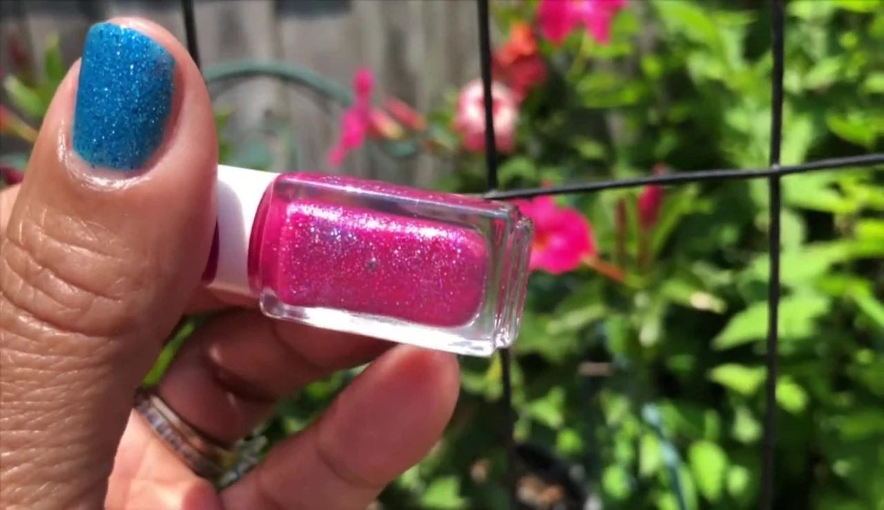 Close-up shot of Pink Unicorn nail polish applied to nails, showcasing its glitter and shine in the sunlight.