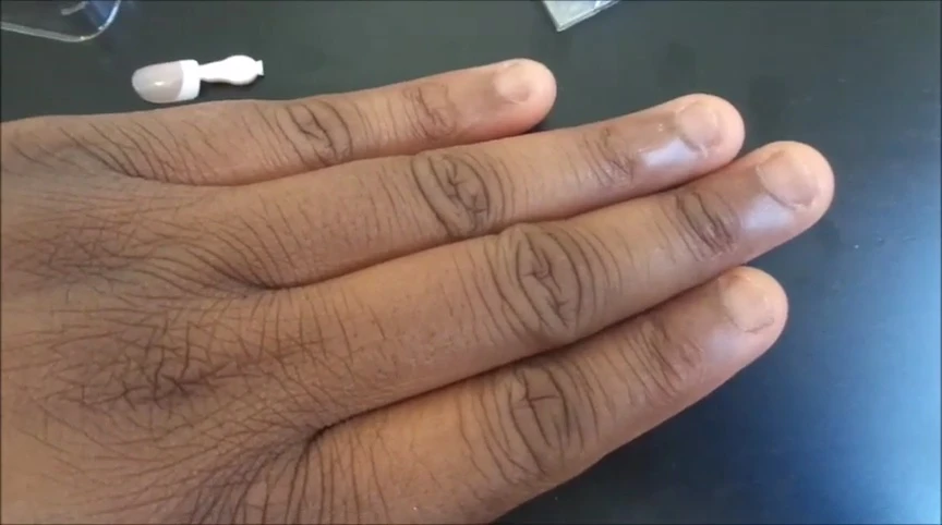 The reviewer preparing her nails for application by pushing back her cuticles.
