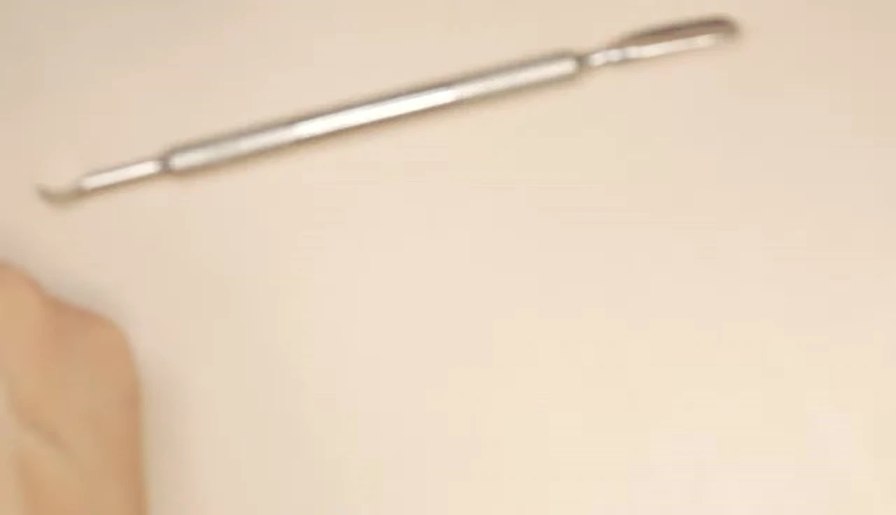 Close-up of the professional cuticle pusher, showcasing its thin, pointed design.