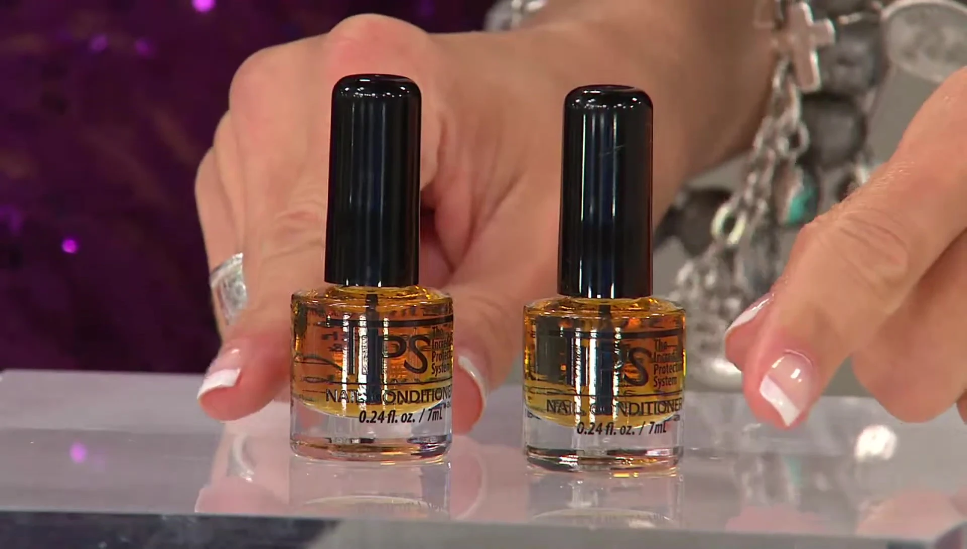 Close-up shot of the T.I.P.S. Nail Conditioner bottle and the presenter emphasizing its conditioning properties.