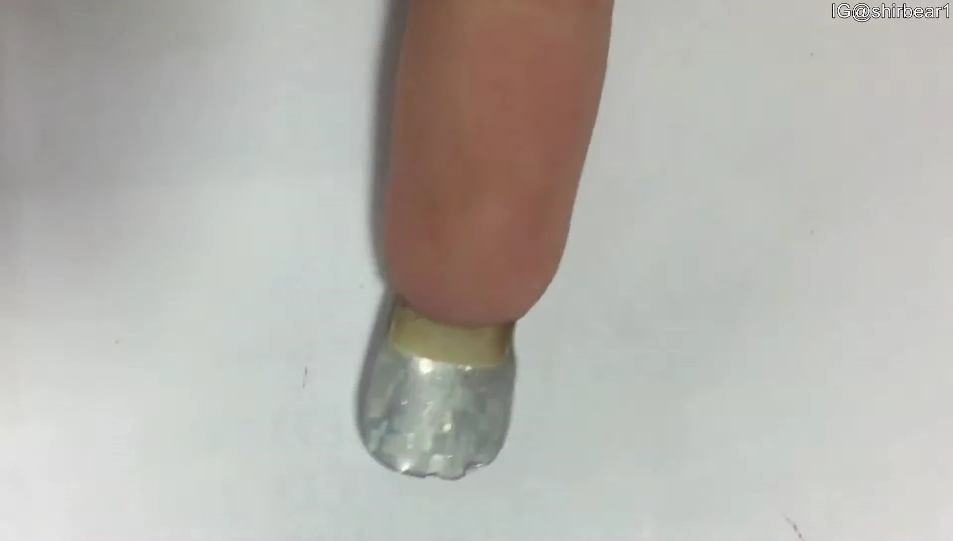 Close up of the hand showing the process of trimming excess nail sticker.