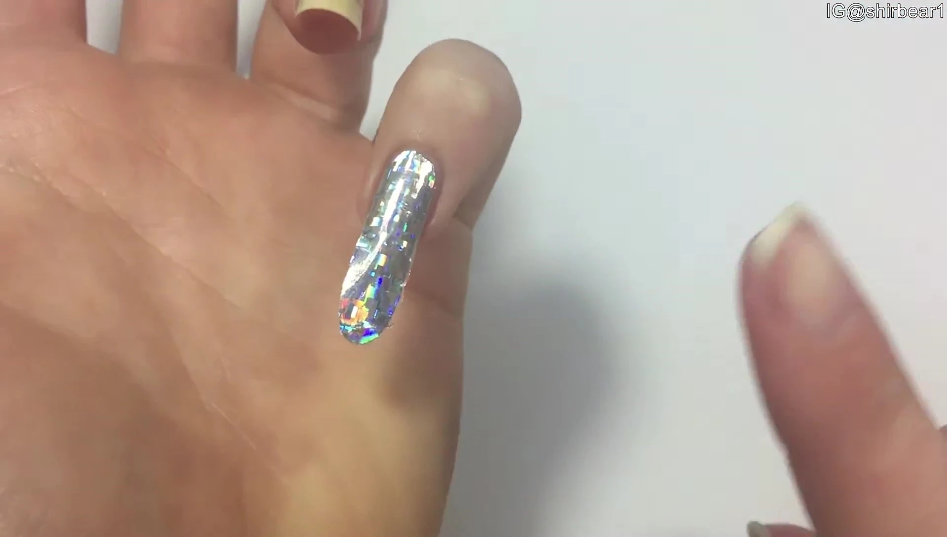 Person testing the size of the sticker on their nail before fully removing the backing.