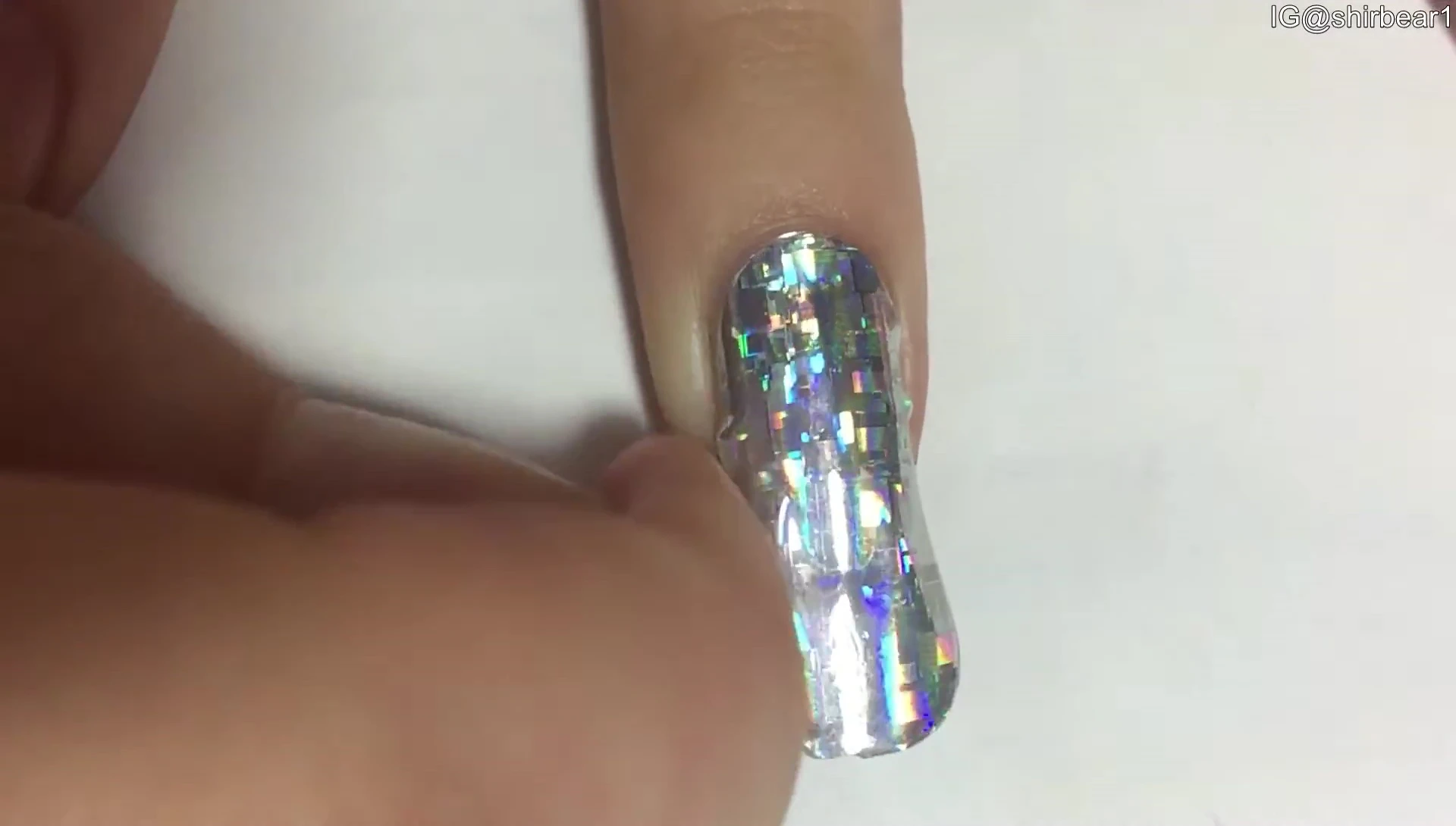 Person smoothing down a nail sticker to remove air bubbles.