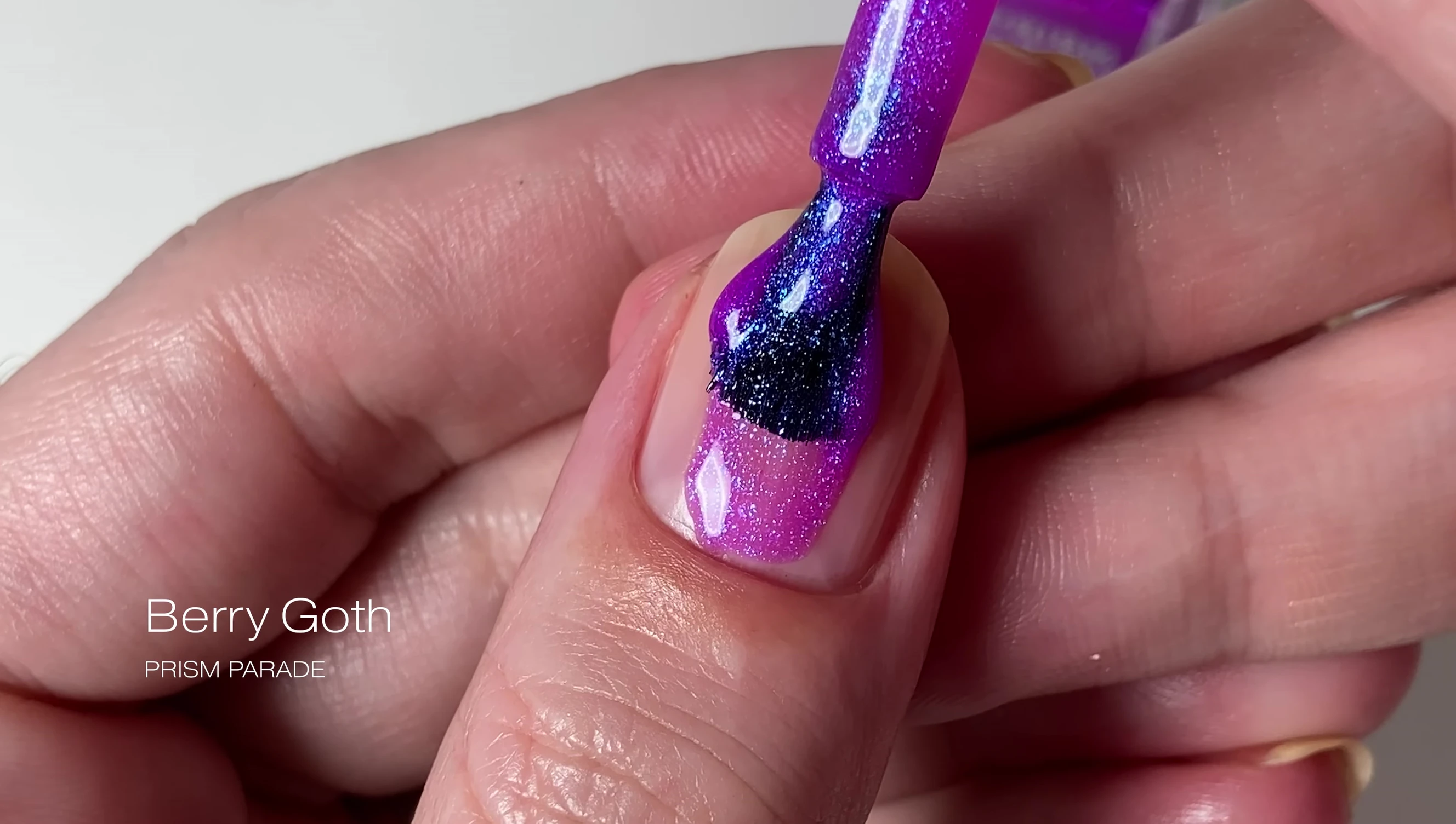 Close-up of Berry Goth nail polish on a finger, showcasing the purple color and blue shimmer.