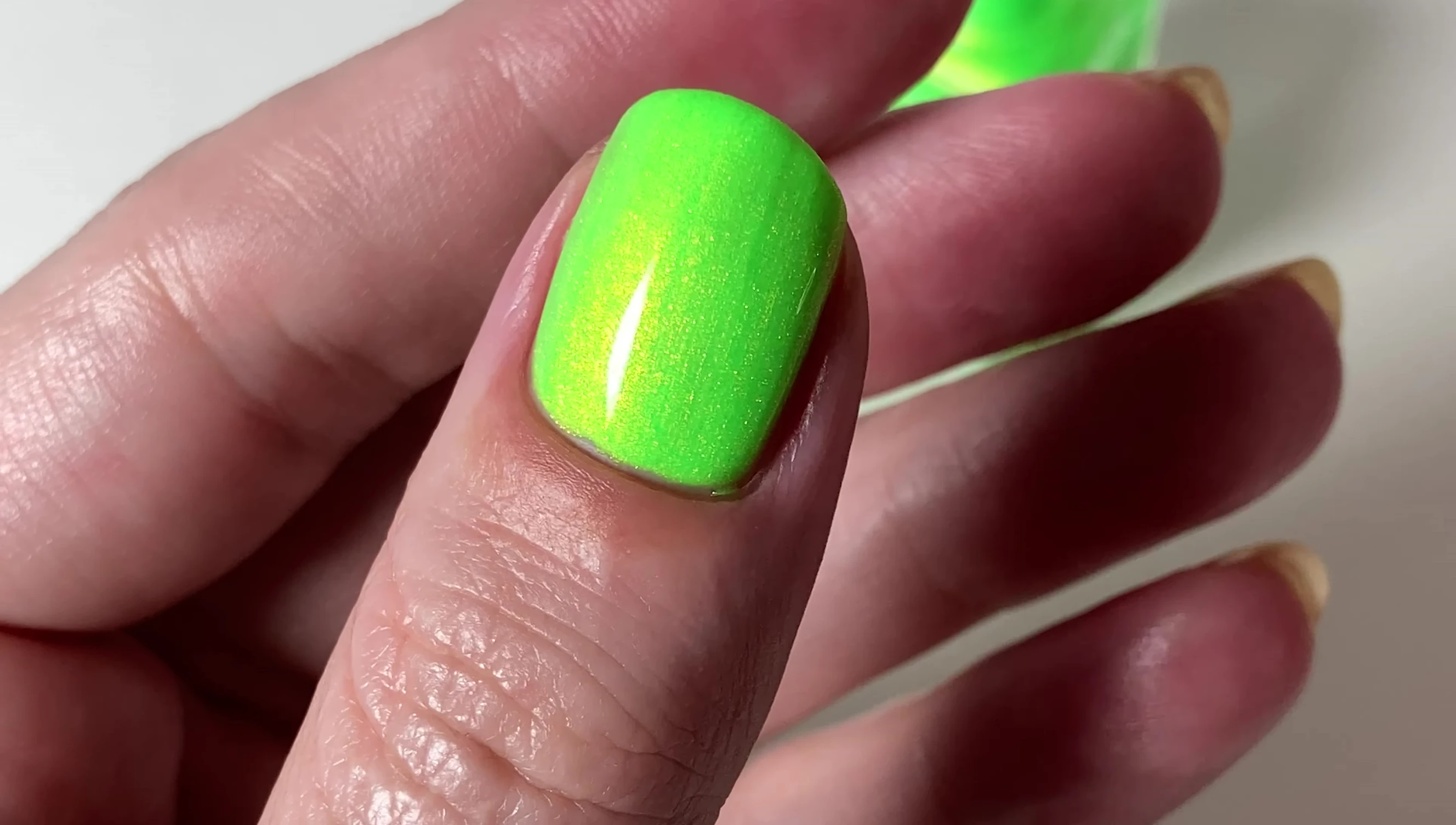 Mal Brat polish on the nails, demonstrating its brightness and shimmer.