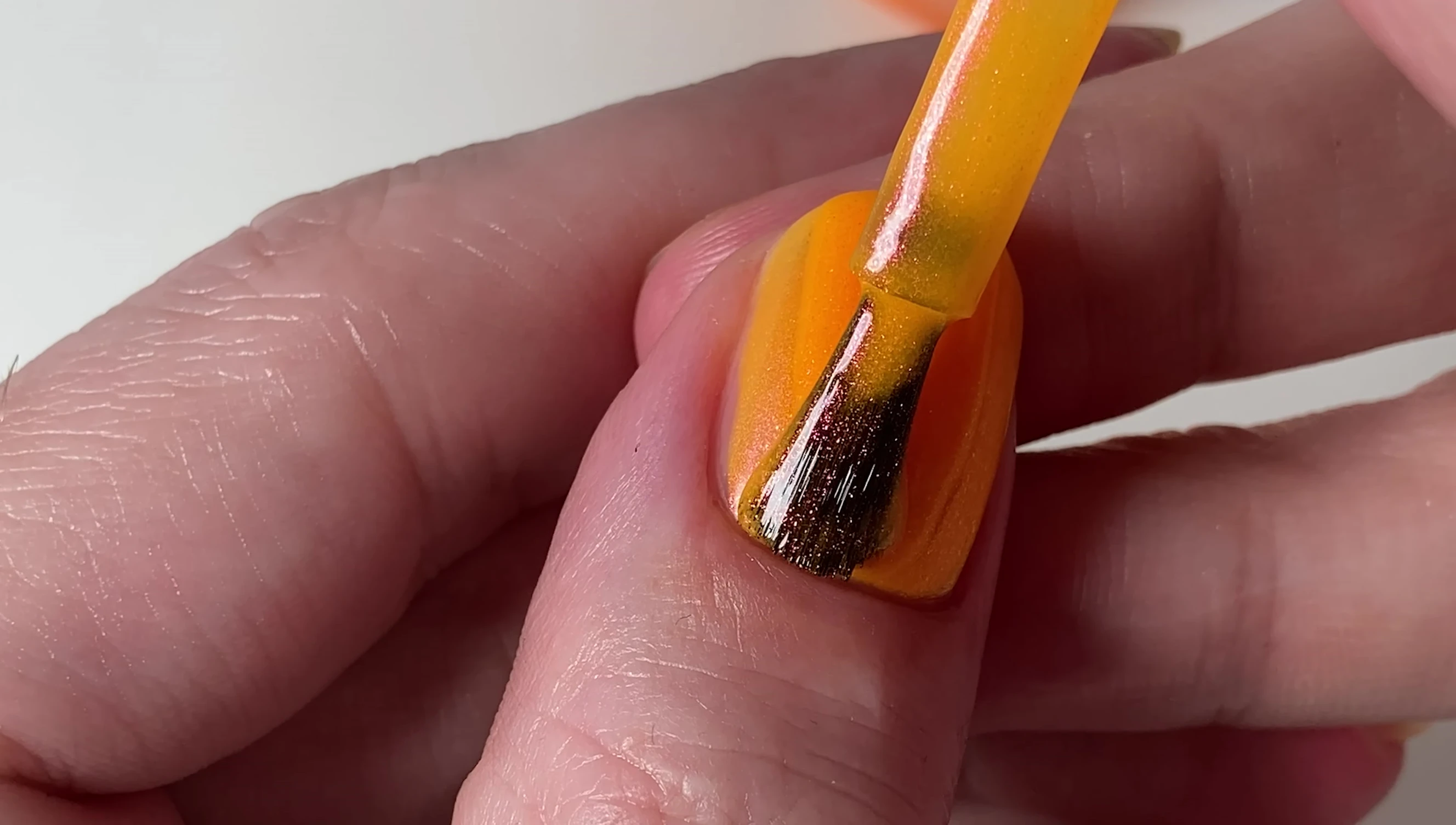 Close-up of Two Straws and One Julius nail polish, showcasing the orange base and pink-orange-gold shimmer.