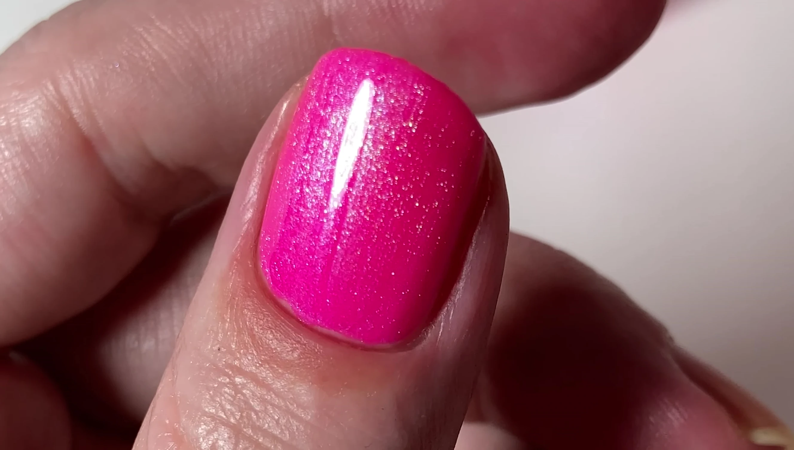 Close-up of Clairvoyant nail polish, highlighting its neon magenta color and multi-toned shimmer.