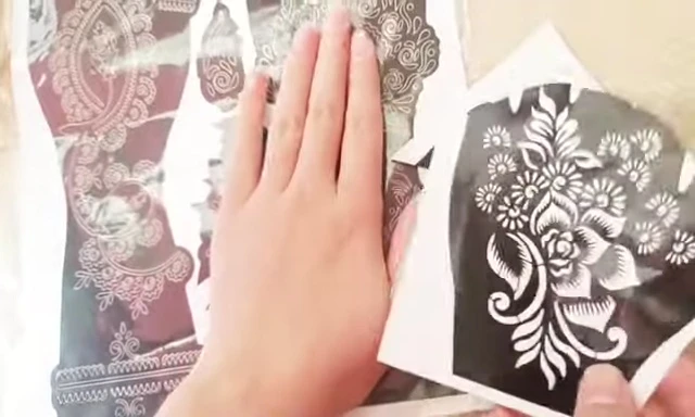 Hand demonstrating the application of a mehndi sticker.
